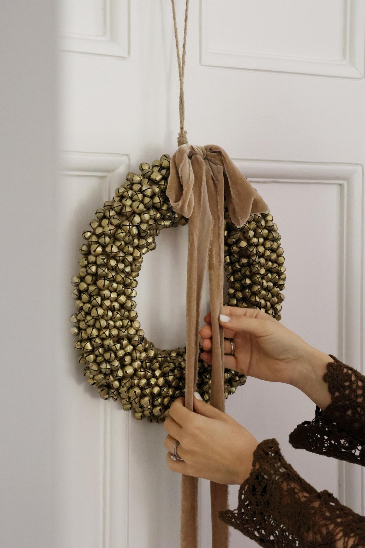 large bell wreath with hanging velvet frayed ribbon on white door 