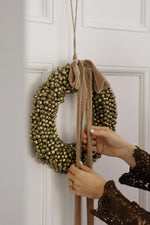 large bell wreath with hanging velvet frayed ribbon on white door 