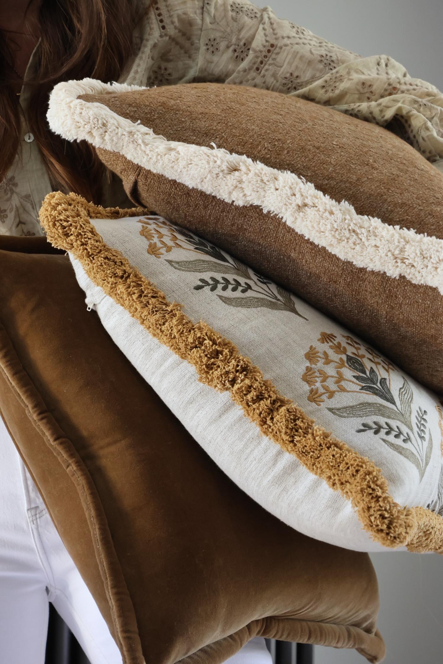 Stack of decorative cushions with brown and beige trim 