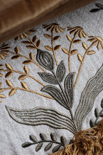 Close-up of embroidered floral design on fabric with brown and green colors.