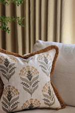 embroidery pattern cushion with floral pattern on a couch against a curtain background