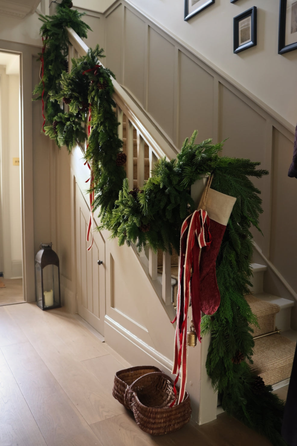 Artificial christmas garlands on a staircase finished with a red stocking and red ribbon