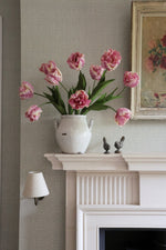 pink tulips in white vase on mantle piece