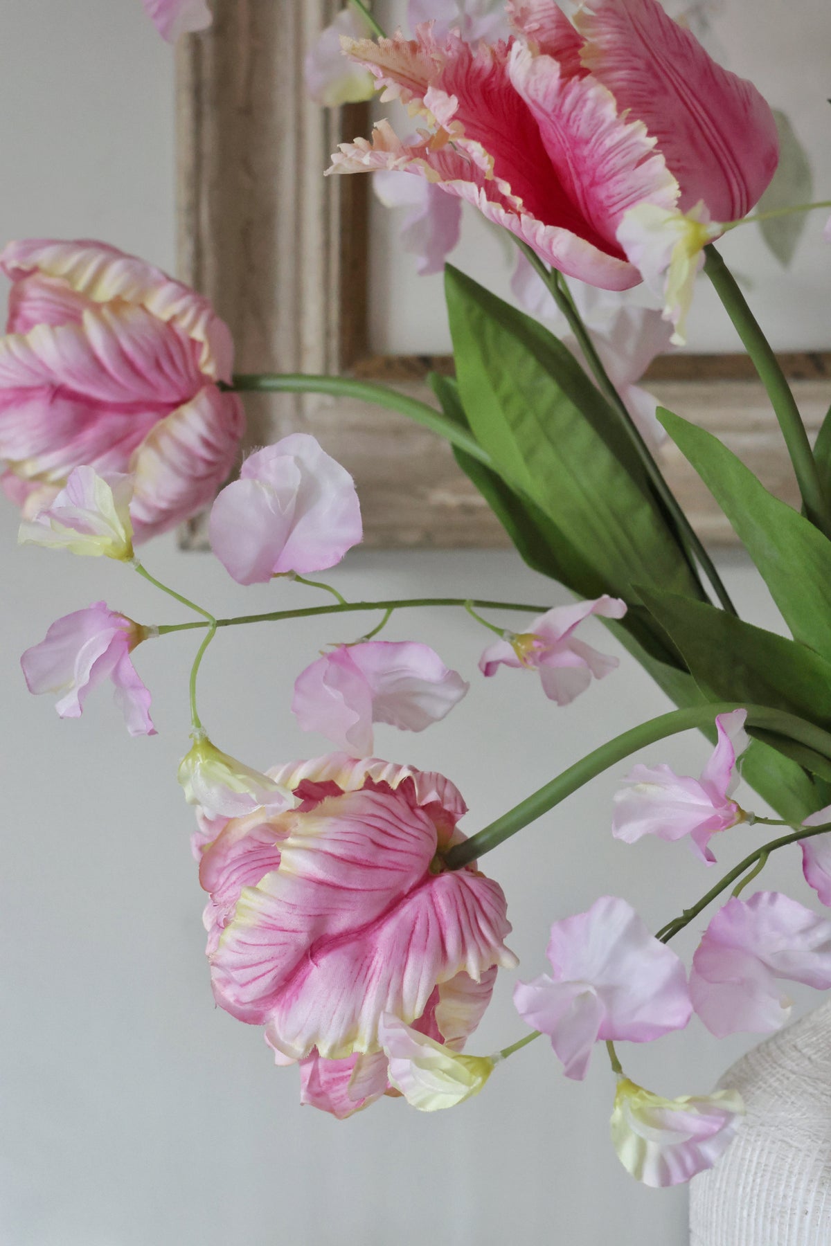 Pink and yellow tulips in a vase against a neutral background