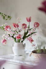 Floral arrangement in a white vase on a marble surface with a blurred background