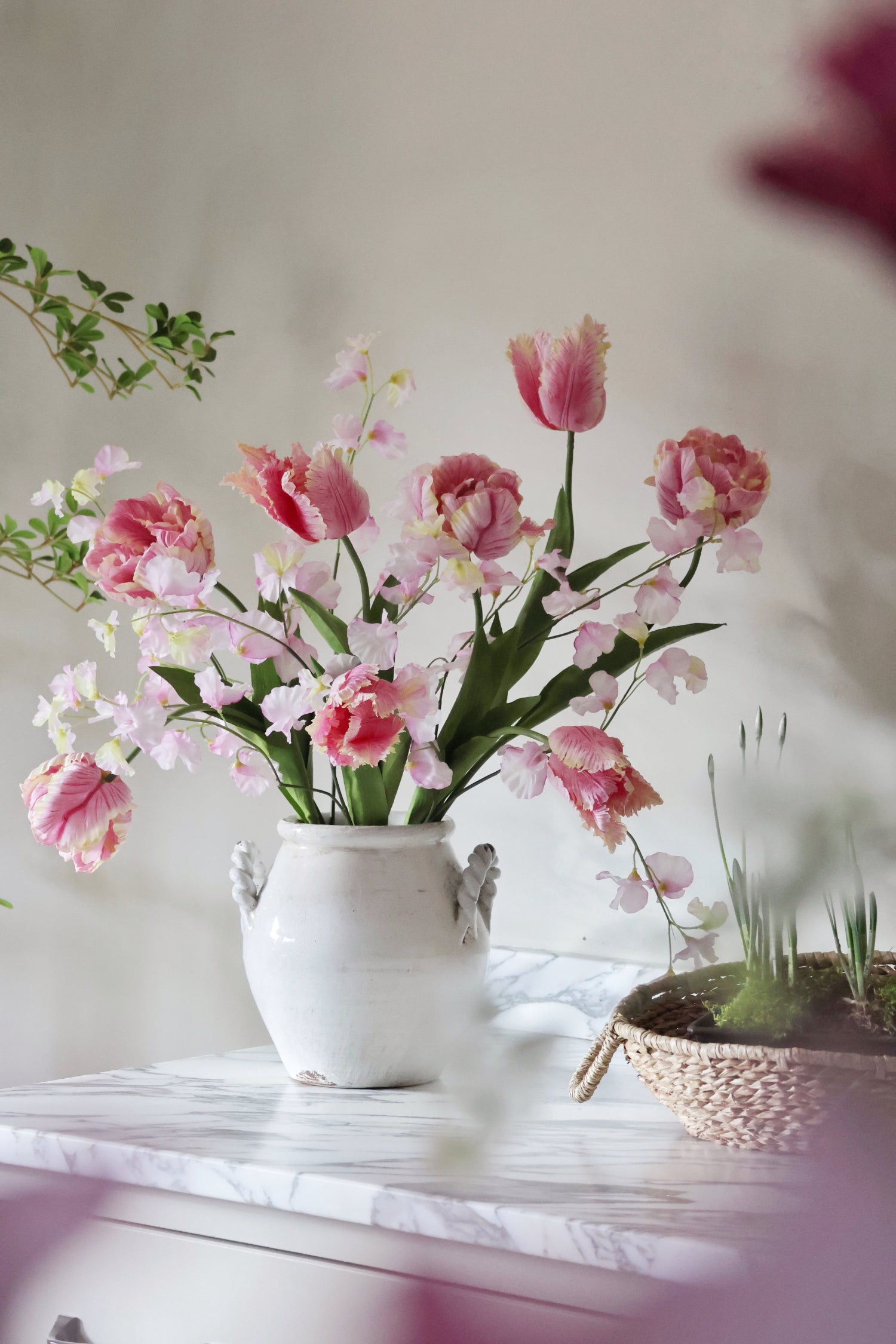 Floral arrangement in a white vase on a marble surface with a blurred background