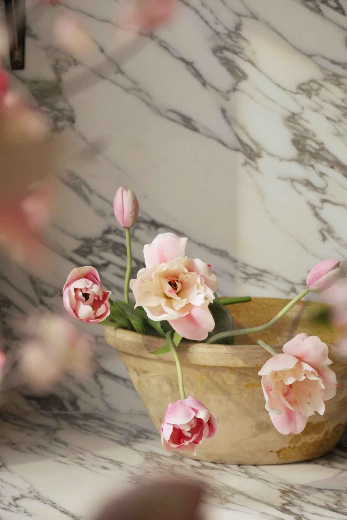 Decorative pink flowers in a beige pot on a marble surface