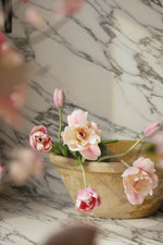Decorative pink flowers in a beige pot on a marble surface