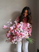Woman holding a bouquet of pink flowers against a plain background
