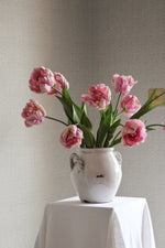 white vase with pink tulips in on textured background 