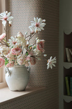 white rustic vase with pale pink flowers in on a windowsill with textured pattern background