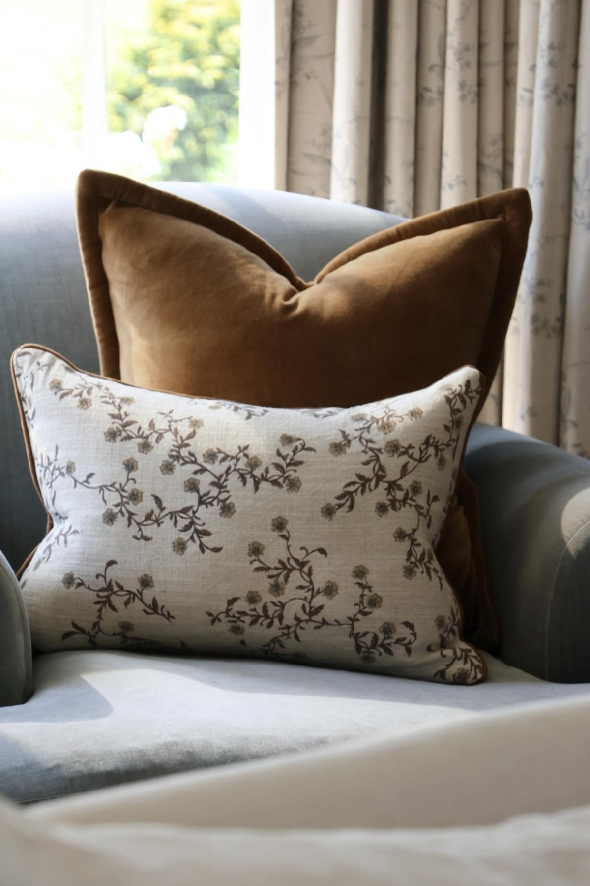 Brown and patterned decorative cushions on a sofa with curtains in the background.