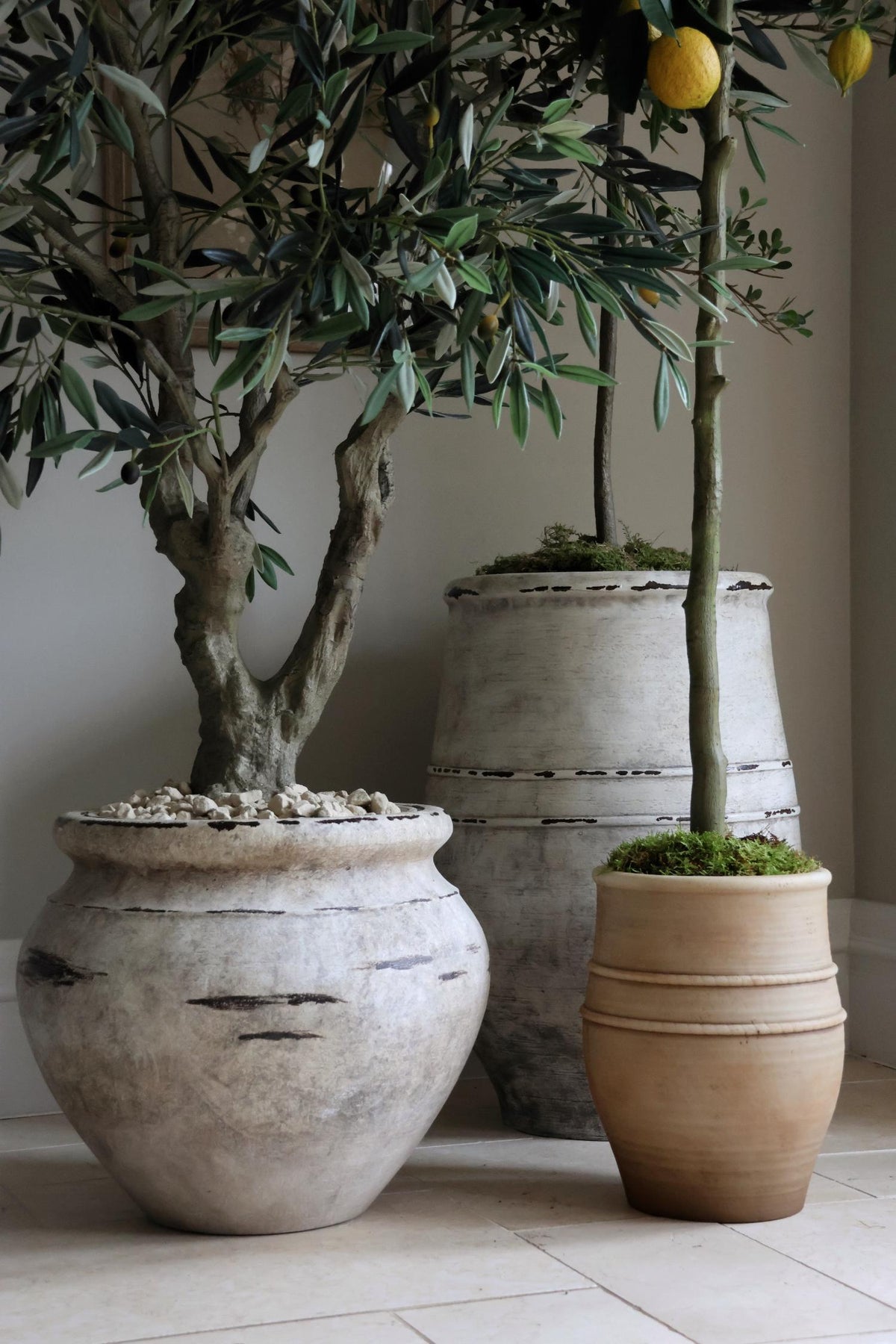 stone effect planters with faux trees in on a tiled limestone floor 