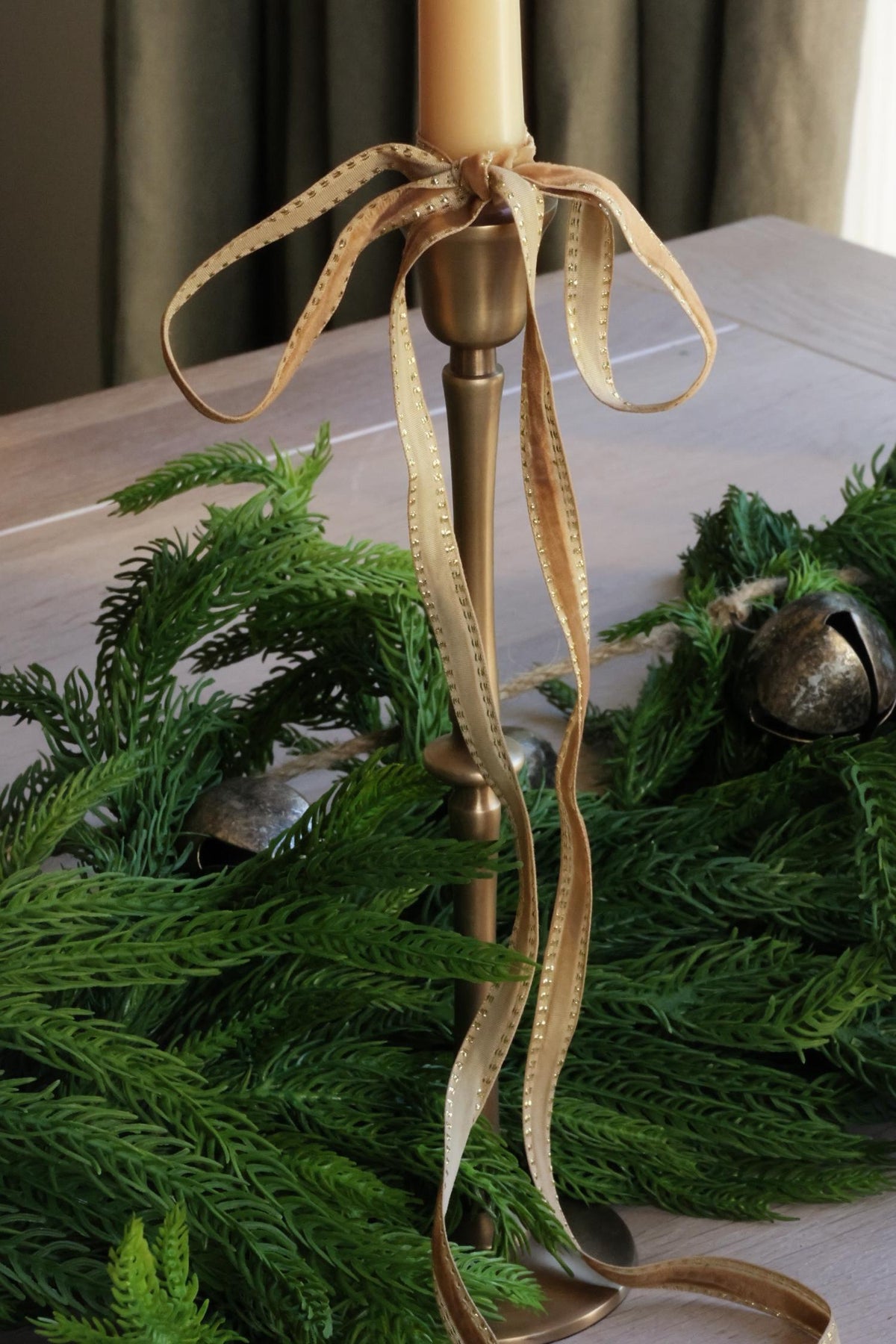 taupe thin velvet ribbon tied in a bow around a tall brass candlestick 