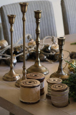 velvet ribbons on wooden spools with brass candlesticks behind on a dining room table 