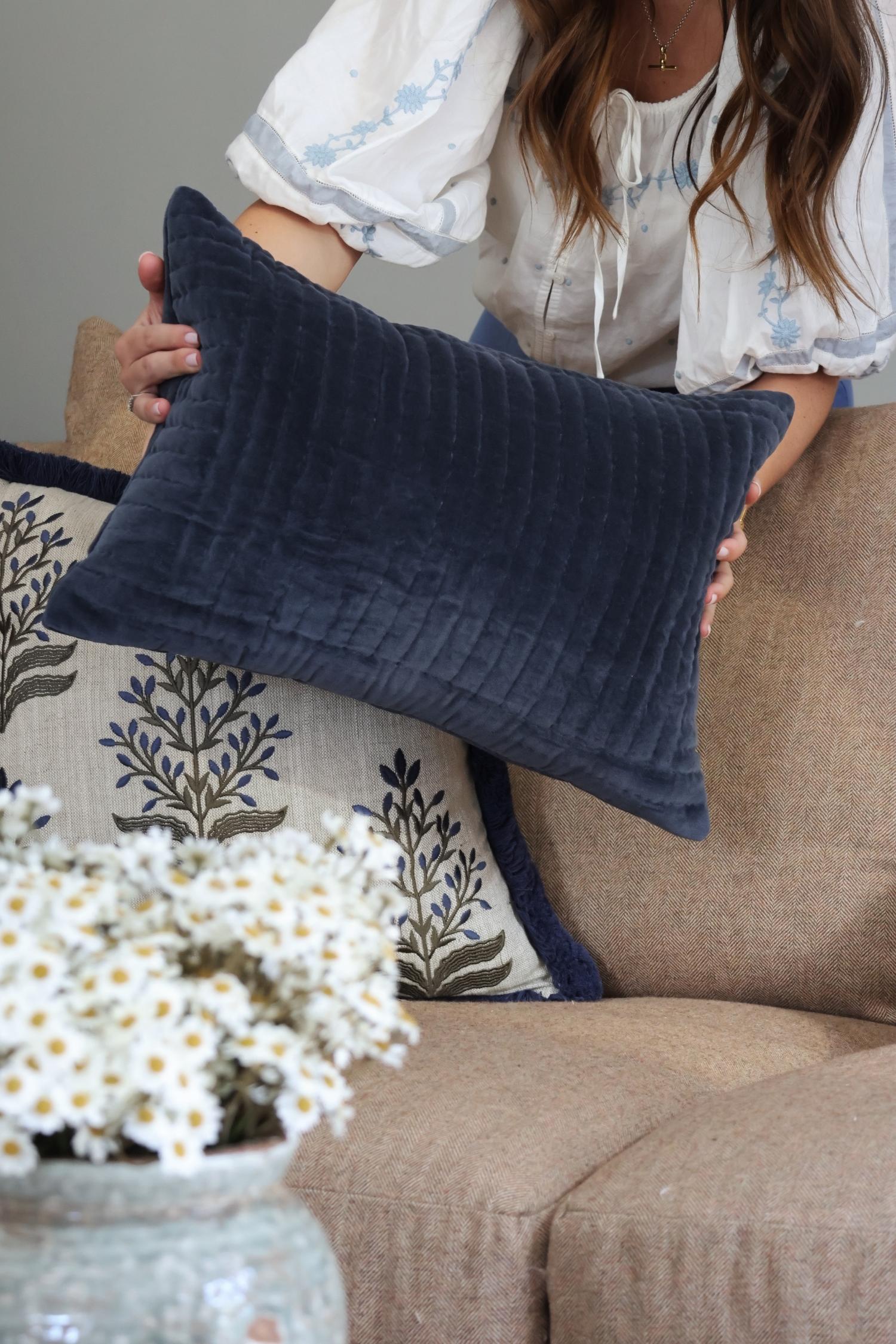 decorative blue velvet cushion on brown sofa