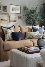 Beige sofa with decorative blue cushions and a coffee table in a living room setting.