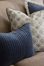 Close-up of decorative blue cushions on a couch with one blue cushion and two patterned cushions .