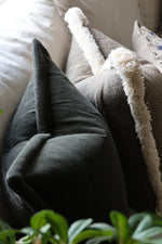 Close-up of textured green cushions on a sofa with a plant in the foreground