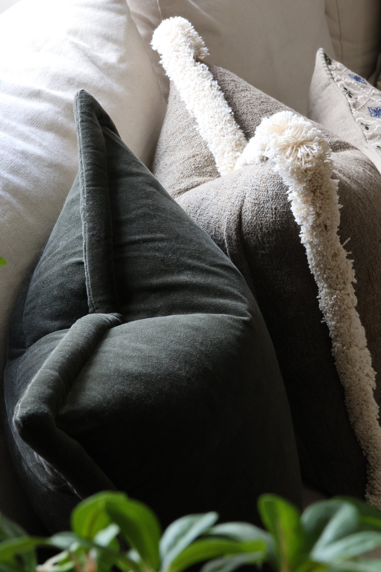 Close-up of textured green cushions on a sofa with a plant in the foreground