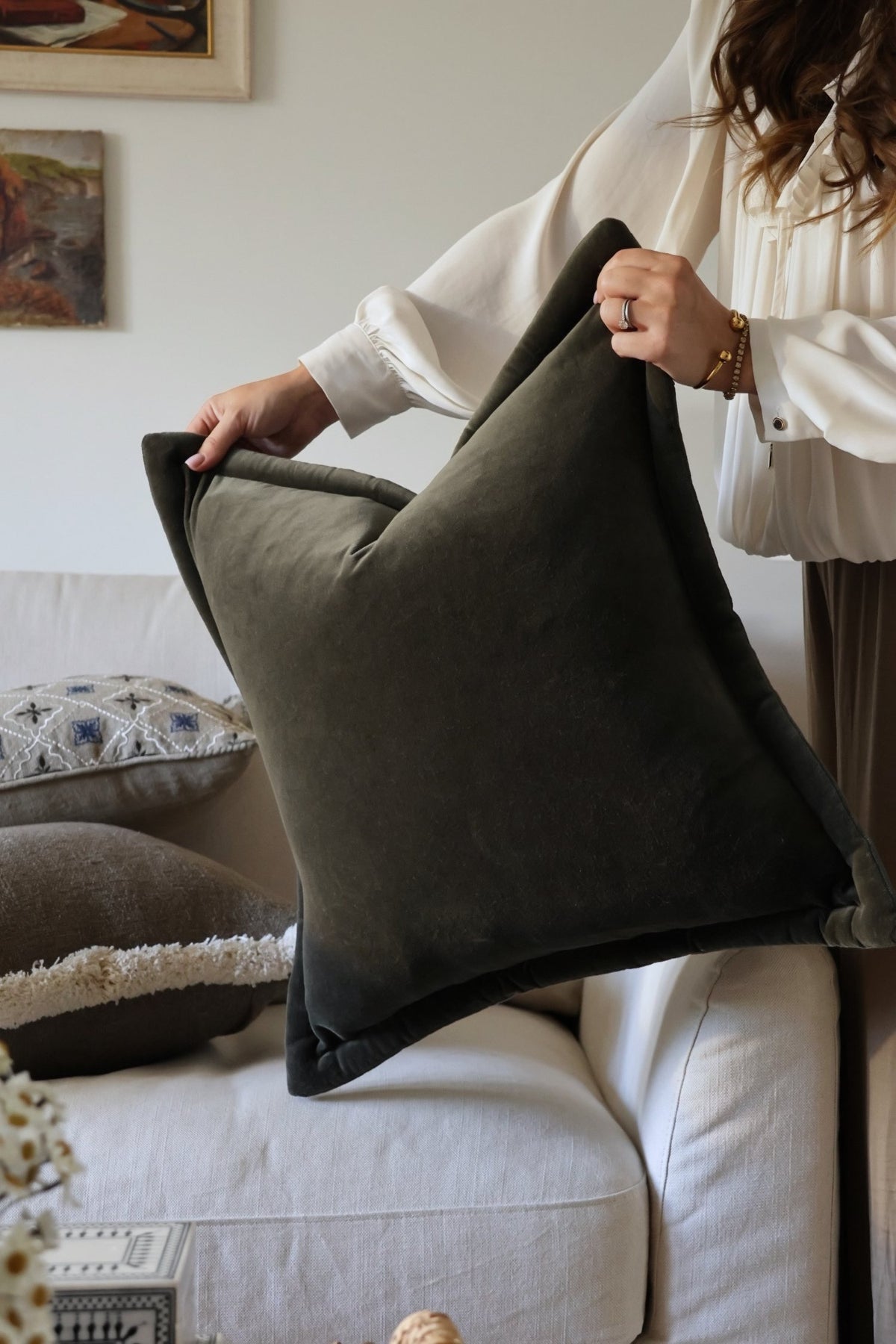Person holding a dark green cushion in a living room setting