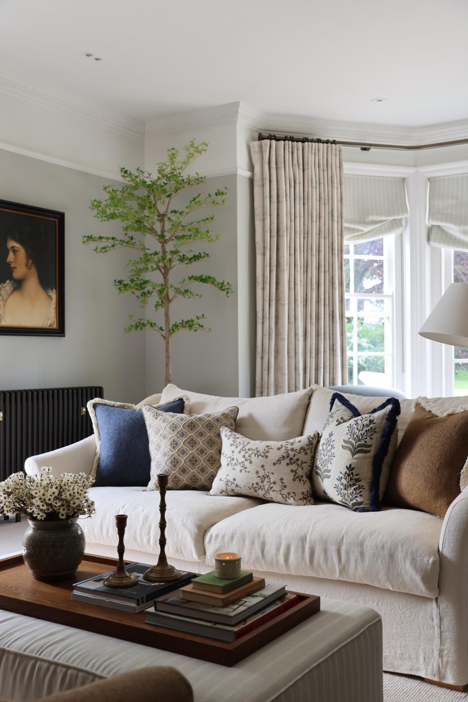 Living room with a white sofa, decorative cushions, and a coffee table with books and a vase.