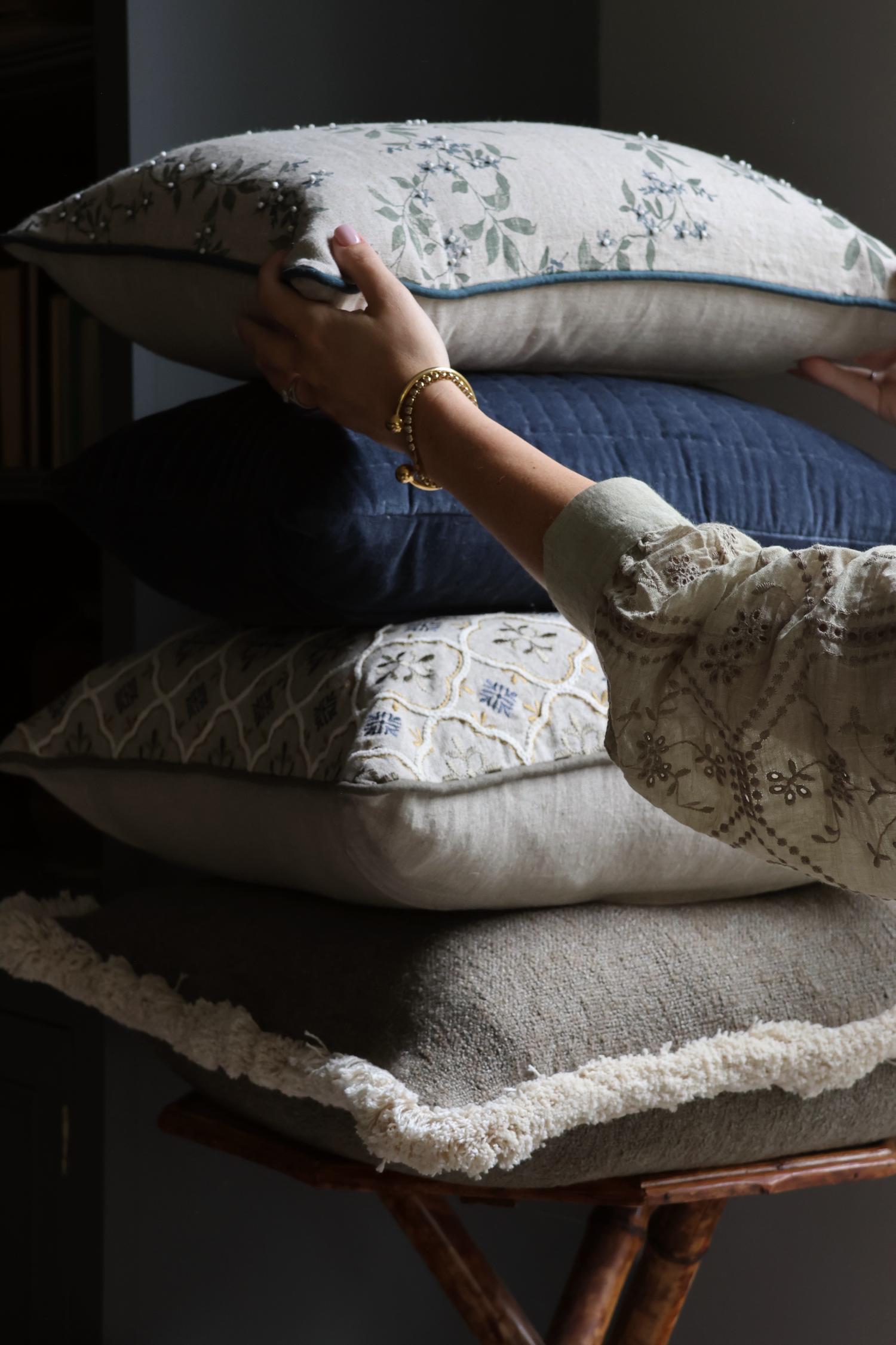 Person arranging decorative cushions on a chair with a dark background