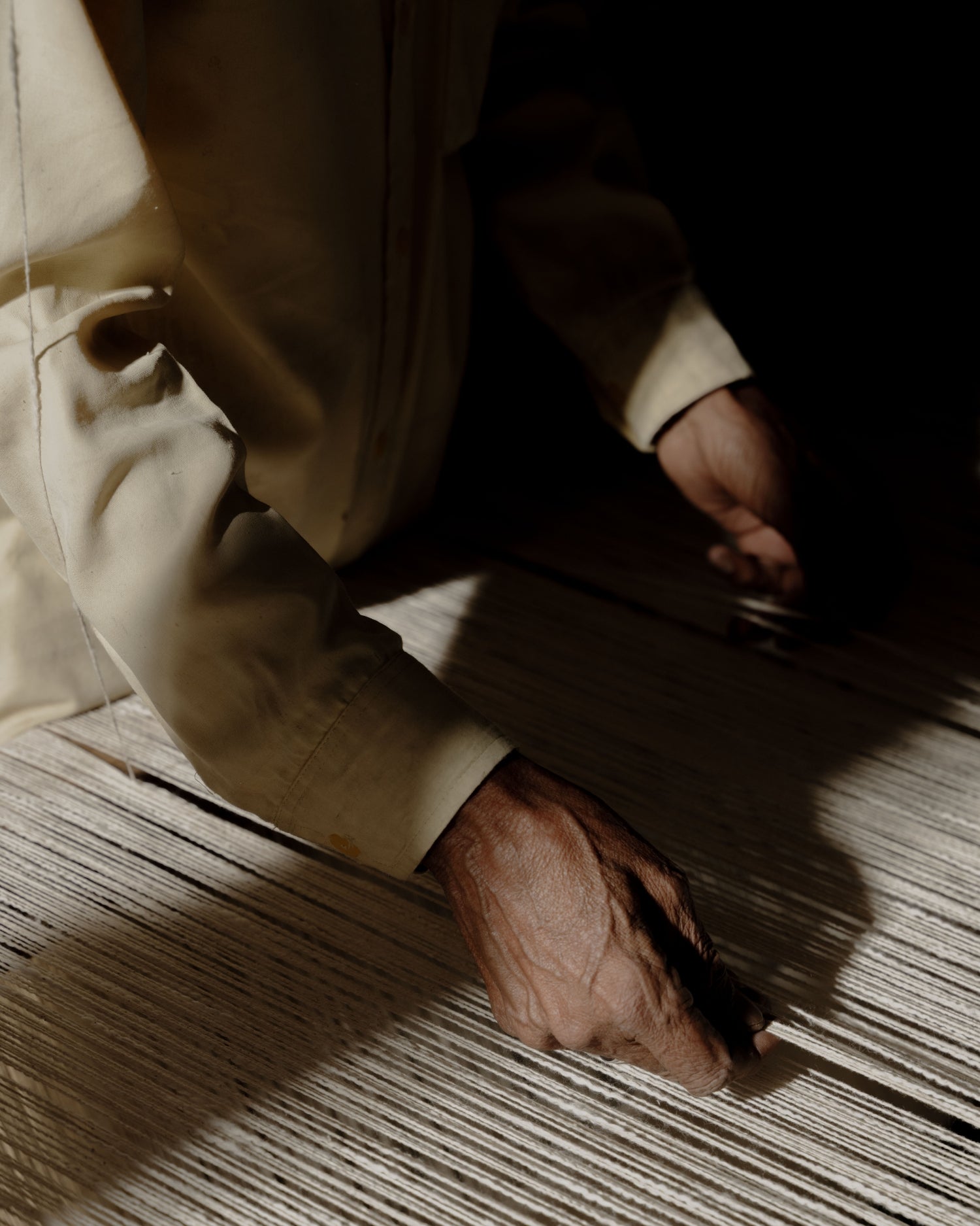 Person wearing a beige suit using traditional artisan weaving techniques