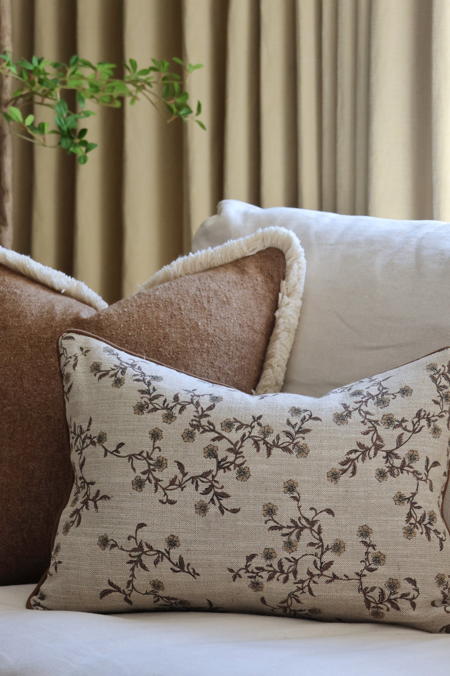 decorative screen printed linen cushion on a beige sofa with curtains in the background