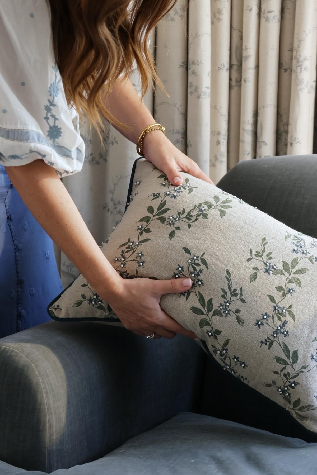 Person holding a floral-patterned cushion against a neutral background