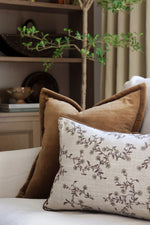 Decorative brown cushions on a sofa with a plant in the background